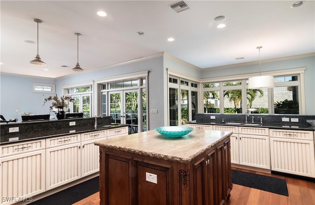 kitchen featuring decorative light fixtures, dark stone counters, and a healthy amount of sunlight