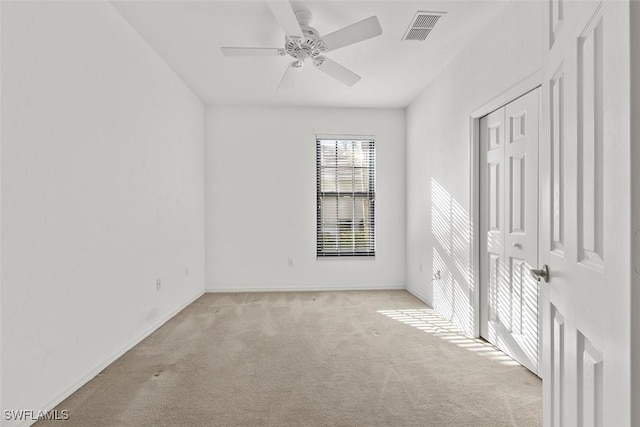 empty room featuring ceiling fan and light colored carpet