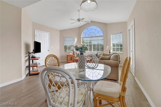 dining area featuring ceiling fan, vaulted ceiling, and light hardwood / wood-style flooring