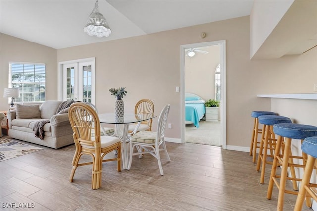 dining space with light hardwood / wood-style flooring, a chandelier, and vaulted ceiling