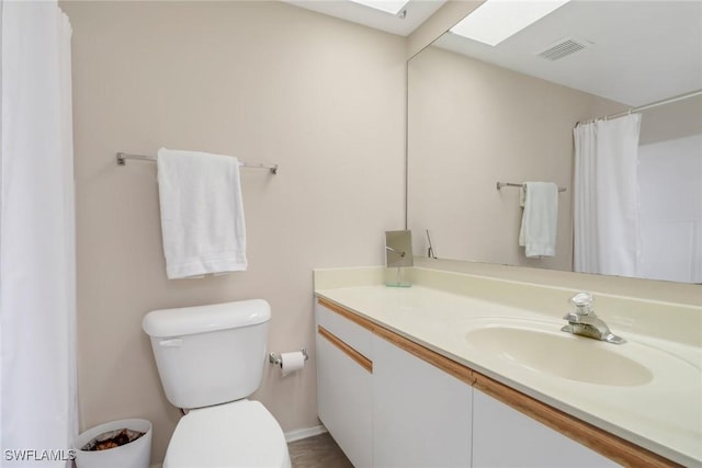 bathroom with vanity, toilet, and a skylight