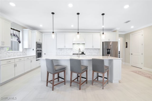 kitchen with hanging light fixtures, a kitchen breakfast bar, an island with sink, and appliances with stainless steel finishes