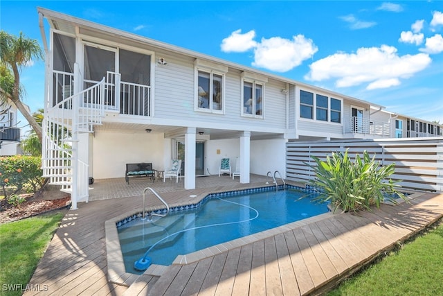 back of property featuring a pool side deck and a sunroom