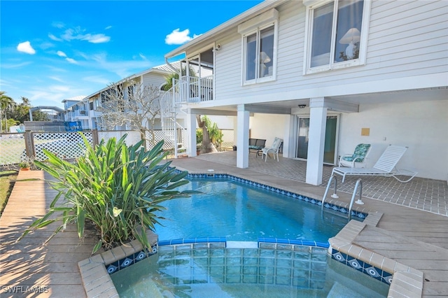 view of pool featuring a patio, stairway, fence, and a pool with connected hot tub