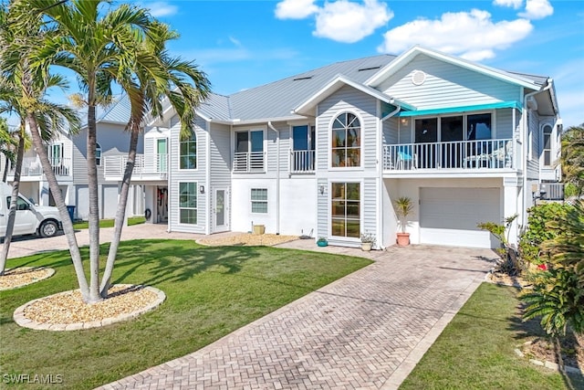 view of front of home featuring an attached garage, cooling unit, a front lawn, and decorative driveway