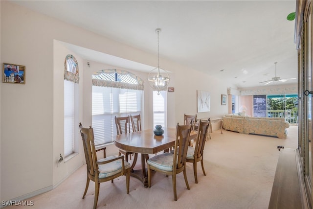 carpeted dining room with ceiling fan with notable chandelier and a wealth of natural light