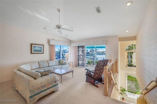 carpeted living room featuring a water view, ceiling fan, and vaulted ceiling