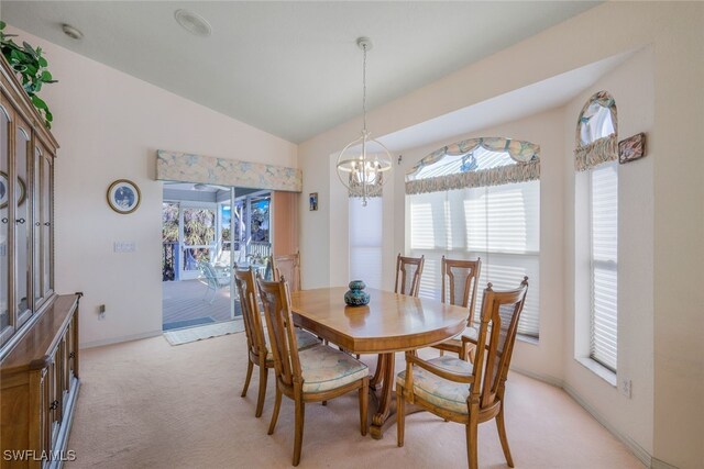 carpeted dining space with vaulted ceiling and a notable chandelier