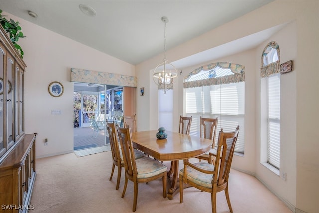 dining space featuring light carpet, baseboards, a chandelier, and vaulted ceiling