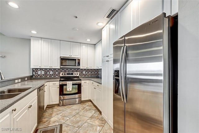 kitchen with stainless steel appliances, white cabinets, decorative backsplash, and sink