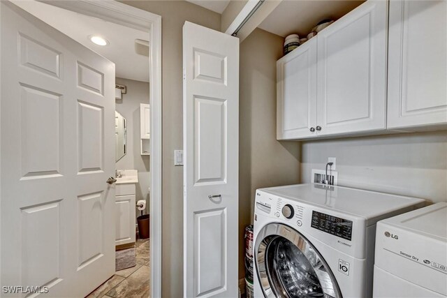 clothes washing area featuring cabinets, washer and clothes dryer, and sink