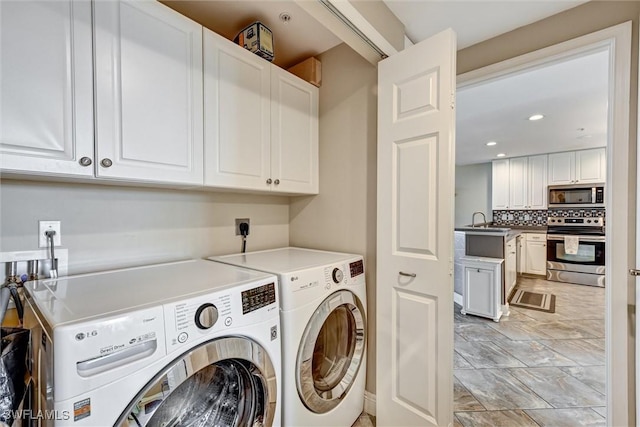 clothes washing area with cabinets, washing machine and clothes dryer, and sink