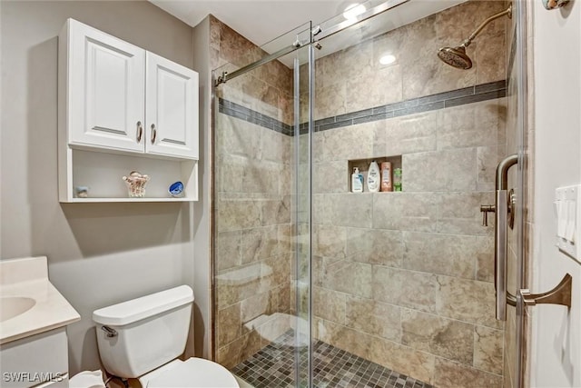 bathroom with a shower with door, vanity, and toilet