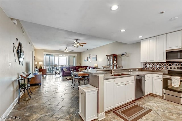 kitchen featuring stainless steel appliances, kitchen peninsula, ceiling fan, sink, and white cabinetry