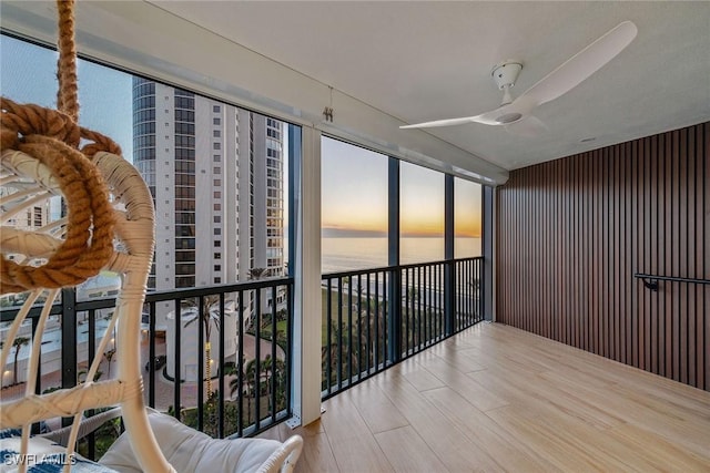 balcony at dusk featuring ceiling fan and a water view