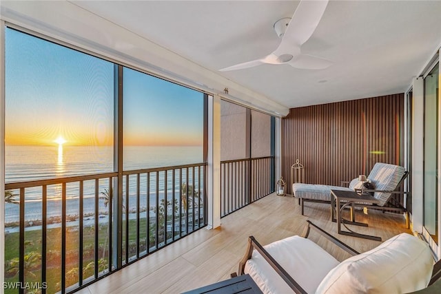 sunroom / solarium featuring ceiling fan, a view of the beach, a water view, and a healthy amount of sunlight