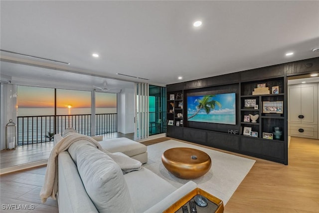 cinema with built in shelves, ceiling fan, and light hardwood / wood-style flooring