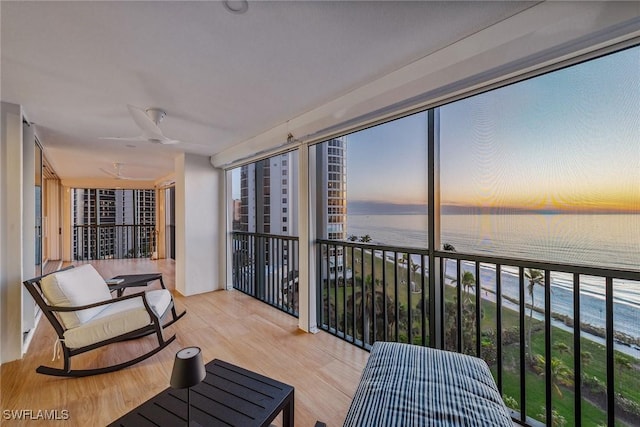 sunroom / solarium with a healthy amount of sunlight, a water view, and ceiling fan