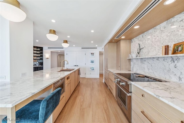 kitchen with light brown cabinets, high end stainless steel range, sink, tasteful backsplash, and light stone counters