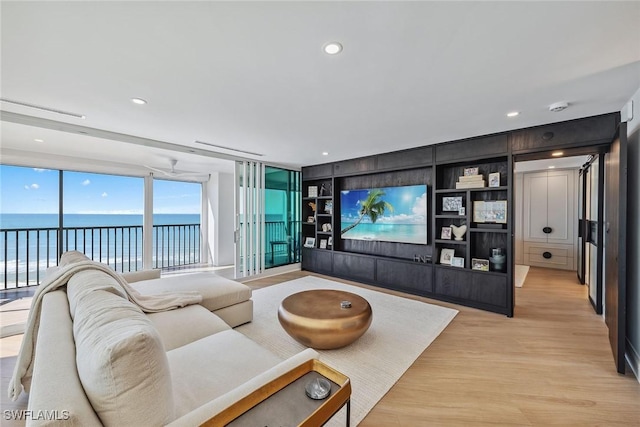 living room with a wall of windows, built in shelves, and light hardwood / wood-style flooring