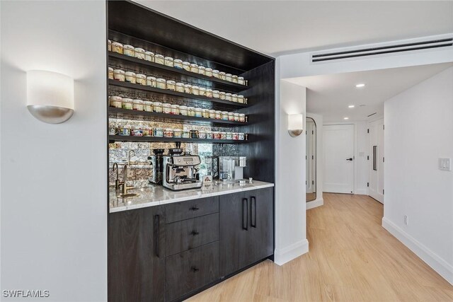 bar featuring light wood-type flooring and dark brown cabinetry