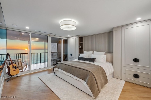 bedroom with light hardwood / wood-style floors, access to exterior, and expansive windows