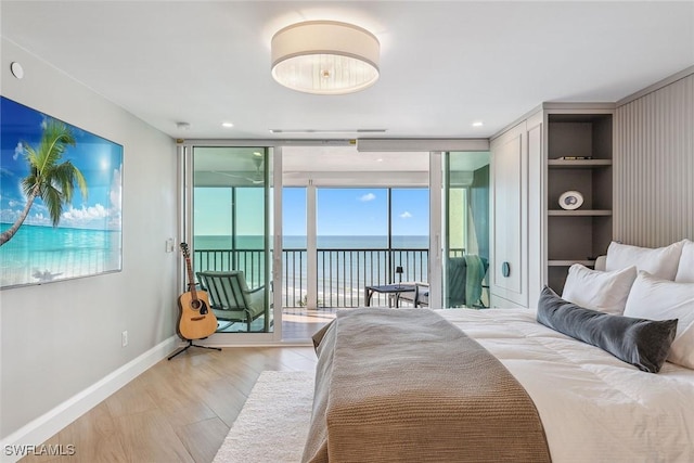 bedroom featuring expansive windows, a water view, access to outside, and multiple windows