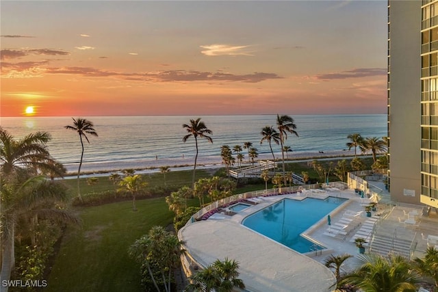 pool at dusk with a water view and a patio