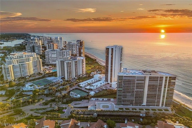 aerial view at dusk featuring a beach view and a water view