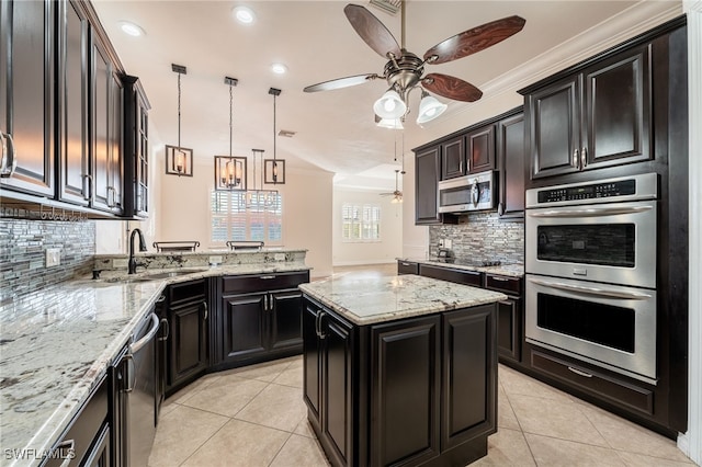 kitchen with pendant lighting, light tile patterned floors, appliances with stainless steel finishes, light stone countertops, and a kitchen island