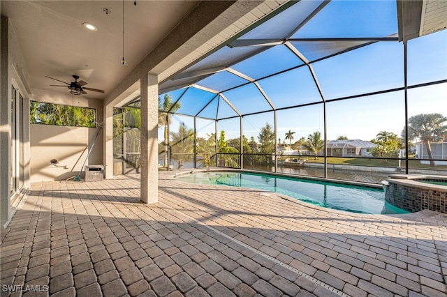 view of swimming pool featuring ceiling fan, a patio, a water view, glass enclosure, and an in ground hot tub