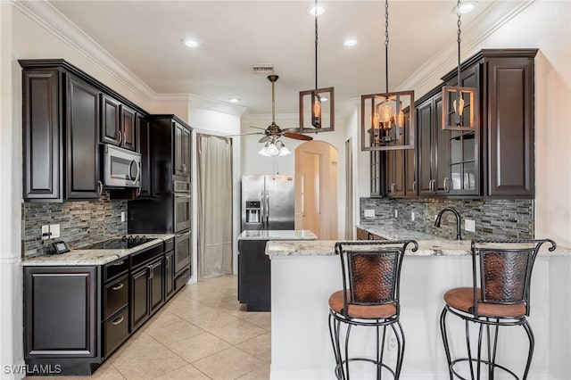 kitchen with pendant lighting, light tile patterned floors, stainless steel appliances, crown molding, and light stone countertops