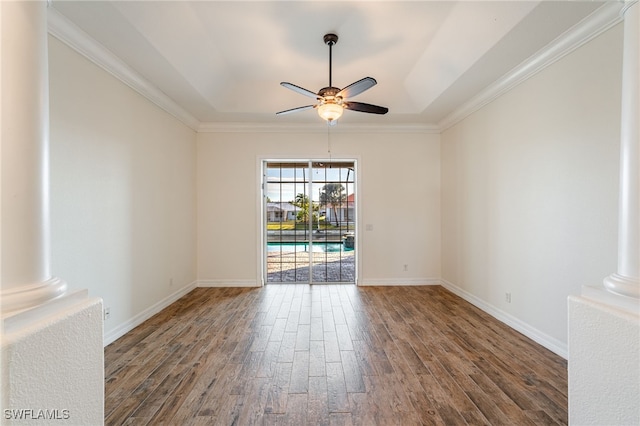 unfurnished room with dark wood-type flooring, ornamental molding, a raised ceiling, ceiling fan, and decorative columns