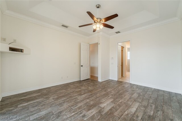 spare room with a tray ceiling, crown molding, dark hardwood / wood-style floors, and ceiling fan