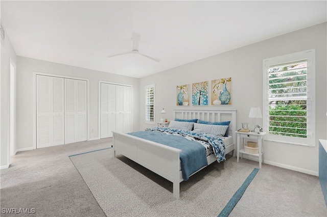 carpeted bedroom with ceiling fan and two closets