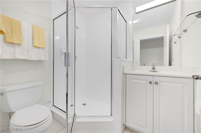 bathroom with tile patterned floors, a shower with door, vanity, and toilet