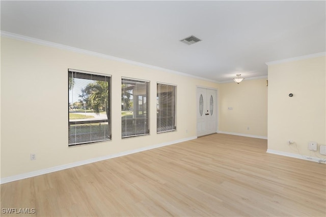 spare room featuring light wood-type flooring and crown molding