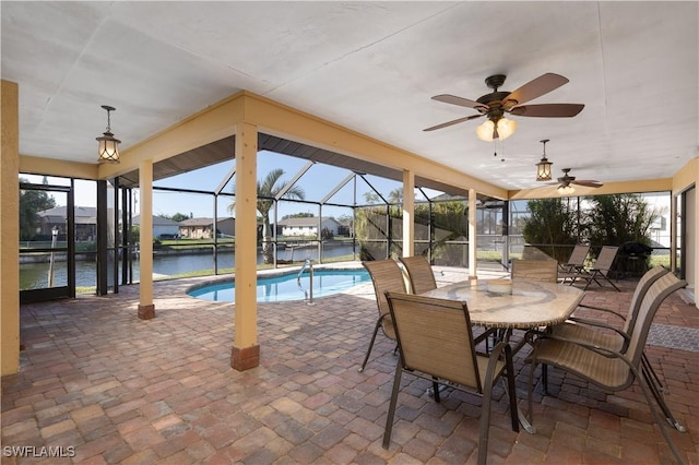 view of pool featuring glass enclosure, a patio area, a water view, and ceiling fan