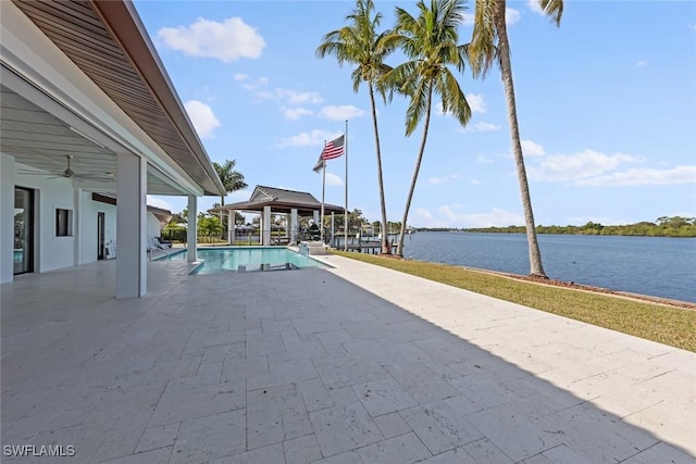 view of swimming pool featuring ceiling fan, a water view, and a patio