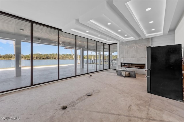 unfurnished living room with a tray ceiling, a wealth of natural light, and a water view