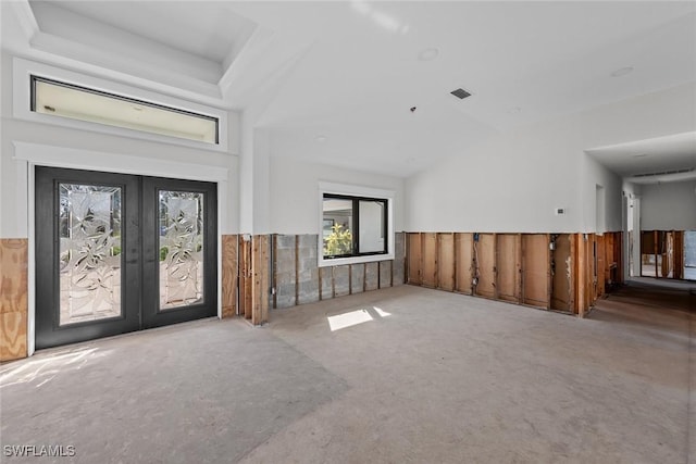 unfurnished living room featuring carpet, vaulted ceiling, and french doors