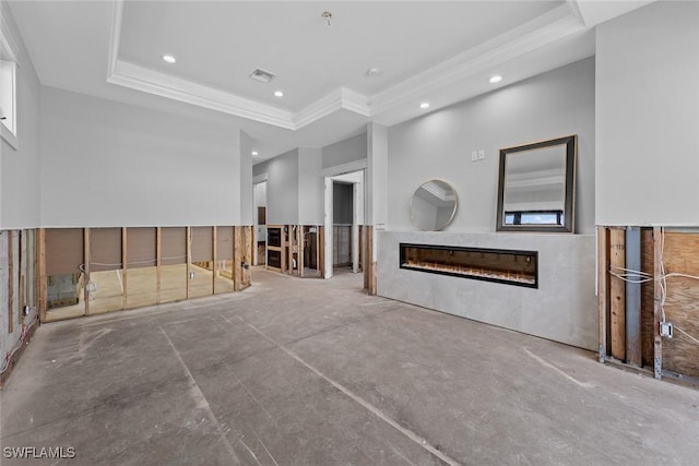 unfurnished living room with a tray ceiling, crown molding, and concrete flooring