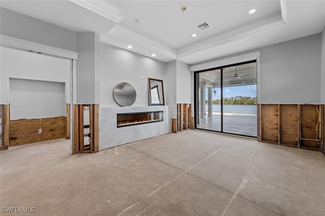 unfurnished living room with concrete floors, a raised ceiling, crown molding, and a tiled fireplace