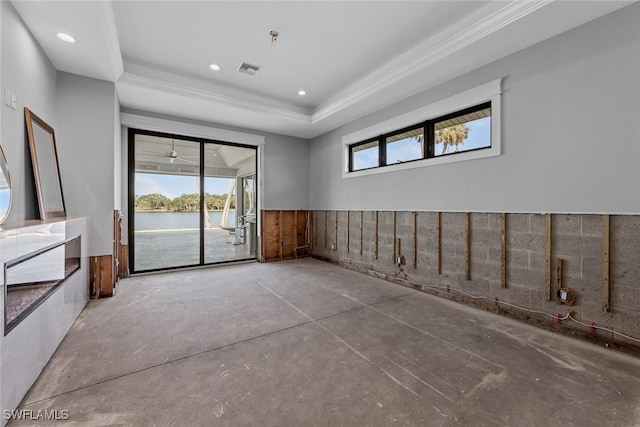 spare room featuring a raised ceiling, a water view, ornamental molding, and concrete floors