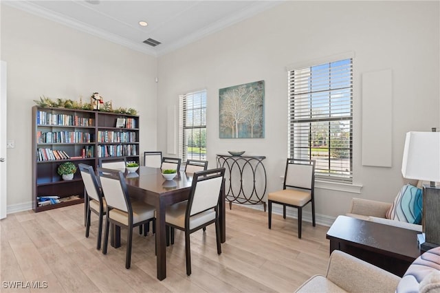 dining space featuring crown molding, light hardwood / wood-style flooring, and a healthy amount of sunlight