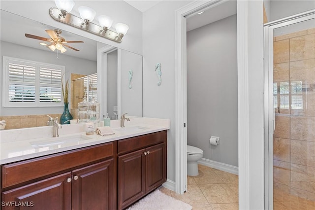 bathroom with ceiling fan, tile patterned floors, toilet, a shower with door, and vanity