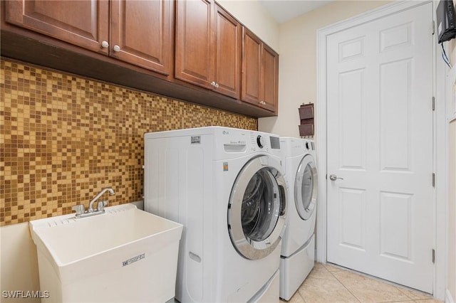 washroom with washing machine and clothes dryer, sink, light tile patterned flooring, and cabinets