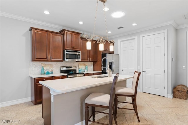 kitchen with ornamental molding, an island with sink, appliances with stainless steel finishes, and tasteful backsplash