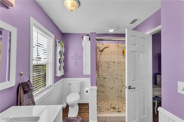 bathroom with walk in shower, vanity, a textured ceiling, wood-type flooring, and toilet