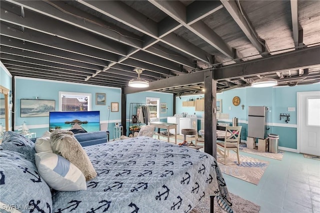 bedroom with stainless steel refrigerator and washer / dryer